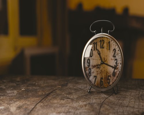Classic alarm clock on wooden table at 7 AM
